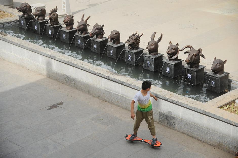 圖為一名市民從獸首旁經(jīng)過。