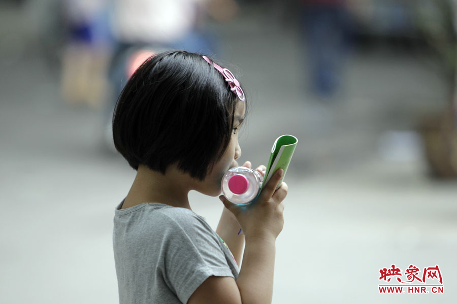 6月7日，鄭州回中考點(diǎn)，一名孩子拿著一瓶礦泉水，等待哥哥走出考場(chǎng)