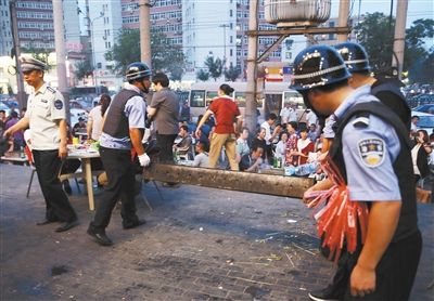 6月13日晚8點(diǎn)，朝陽(yáng)路和青年路交叉口西側(cè)，一次聯(lián)合執(zhí)法行動(dòng)中，輔警與協(xié)管抬走商戶的燒烤用具。新京報(bào)記者 尹亞飛 攝