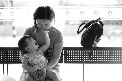 昨日，肯德基京廣中心店門口，姜女士提起跟養(yǎng)父母的關(guān)系時(shí)落淚，懷中9個(gè)月的女兒笑著跟她玩。新京報(bào)記者 薛珺 攝