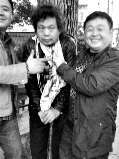 兩名接訪人員與患有癌癥的訪民段新德合影時，面帶笑容擺出勝利的手勢。