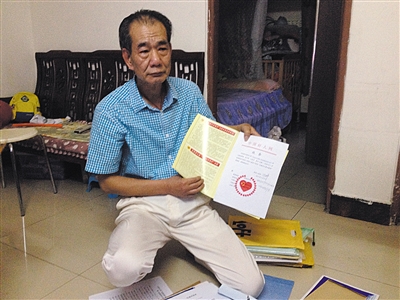 翻出一家網(wǎng)站贈(zèng)予的“中國(guó)好人”證書，區(qū)少坤單膝跪在地上，“你看，我是中國(guó)好人啊。” 范春旭 攝