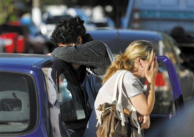 27日，遇難者親友在火災現(xiàn)場旁哭泣。