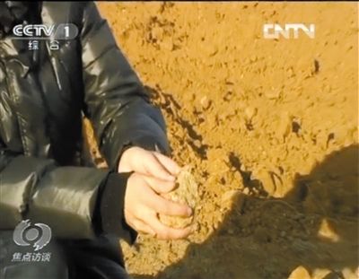 麻剛沙系麻剛石粉碎而成。記者找到一塊麻剛石，一捏就碎成粉末，硬度非常差。央視截圖