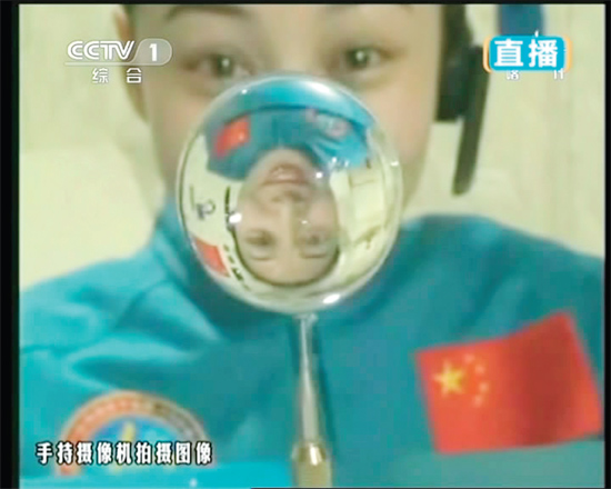 王亞平的倒影出現(xiàn)在水球中。新華社發(fā)（視頻截圖）