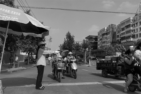 昨日，開封市區(qū)一名協(xié)管員在指揮群眾過馬路