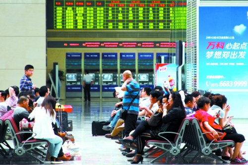 候車大廳溫度很高，一名乘客一手扇風(fēng)、一手擦汗