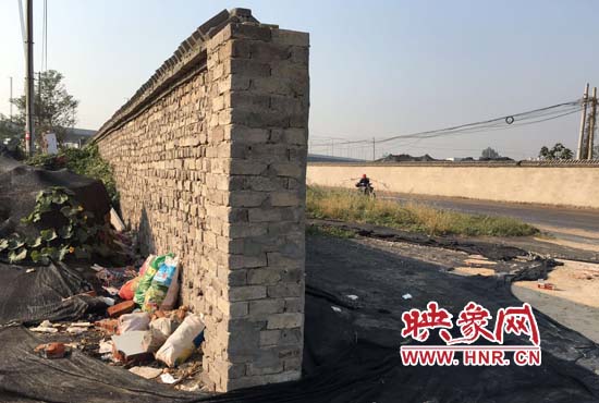 一墻之隔，一邊是道路，一邊是垃圾和荒草，市民質(zhì)疑其為遮羞墻。