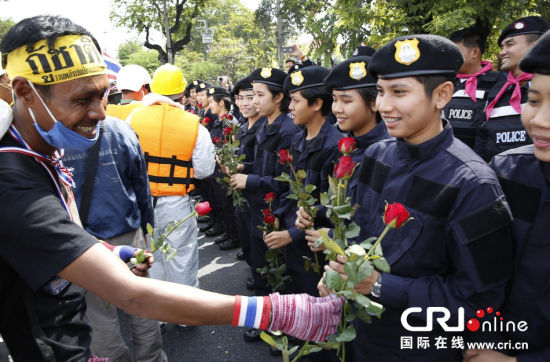 2013年12月03日,曼谷總理府與曼谷警署允許反政府示威民眾進(jìn)入,雙方進(jìn)入暫時(shí)“停戰(zhàn)”狀態(tài)迎接泰王生日。曼谷警察總署,女警們手持鮮花送給反政府示威民眾。圖片來源:Manish Swarup/東方IC