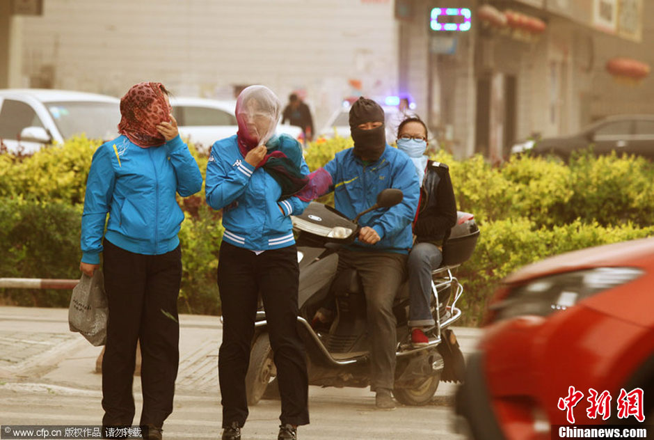 2014年04月23日，新疆維吾爾自治區(qū)吐魯番地區(qū)，市民戴著口罩行走在大風沙塵中的吐魯番市街頭。