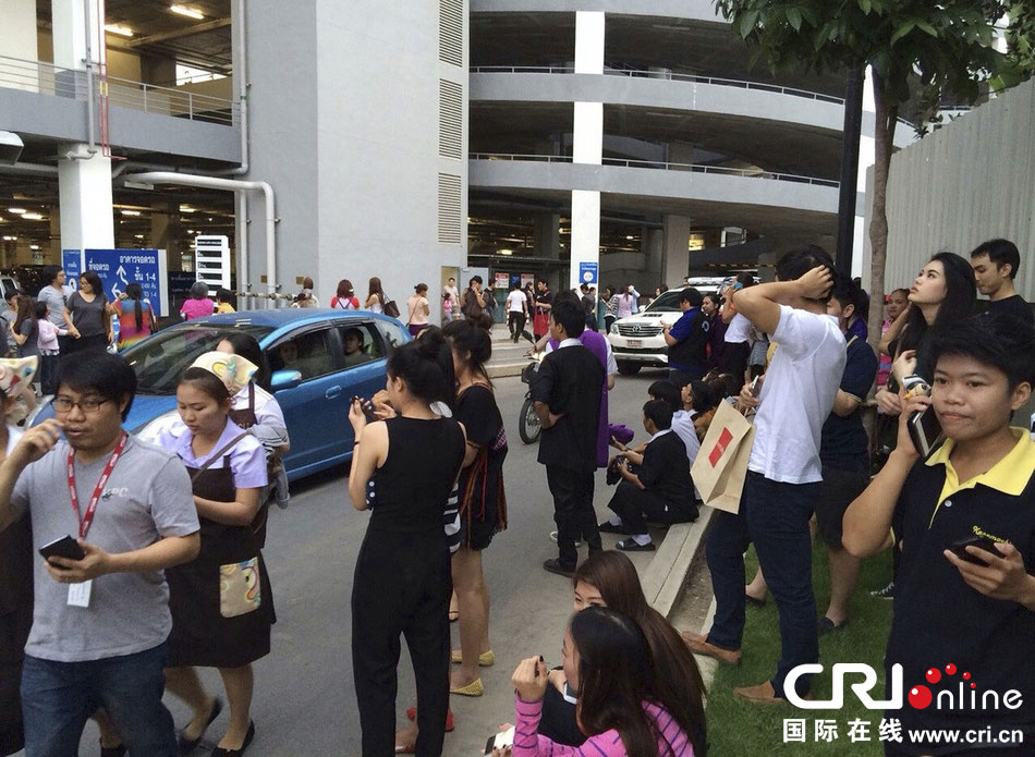 當?shù)貢r間2014年5月5日，泰國清萊，工人們站在一棟大樓外避難。