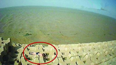 孫正龍游上岸，趴在海邊精疲力盡。