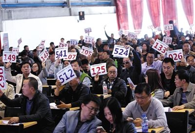 競(jìng)拍者正在練習(xí)舉牌動(dòng)作，以便拍賣時(shí)讓工作人員看清號(hào)牌。