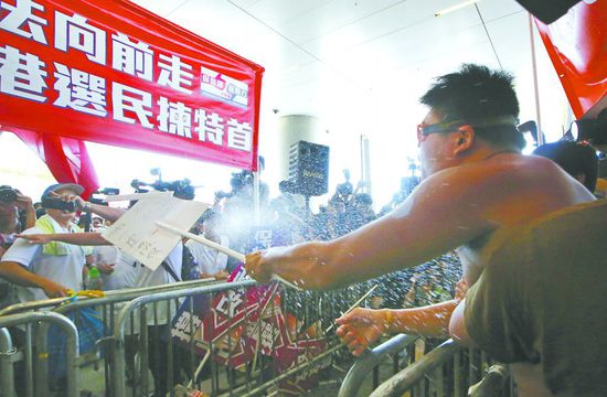 17日，在香港立法會外，一名反對政改的男子向支持派人群投擲標(biāo)牌。