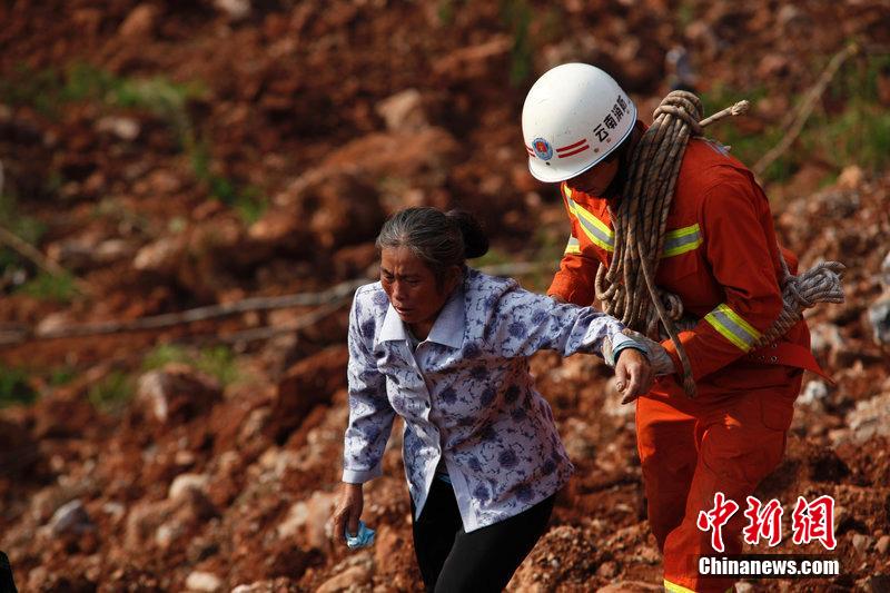 一位消防戰(zhàn)士將一位失去親人的老人扶離滑坡點。