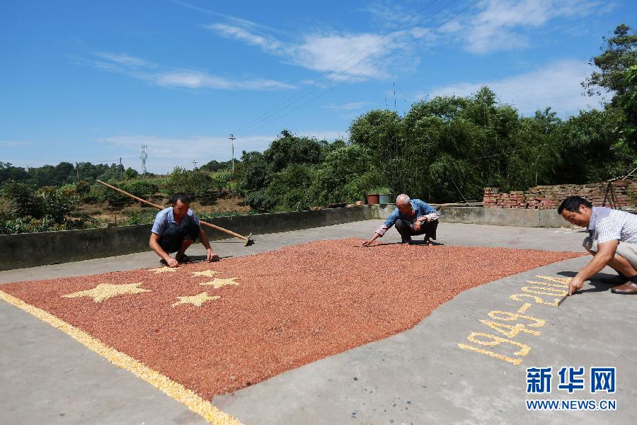 村民馬玉明（左一）用豐收的高粱和玉米在院壩里擺國旗為祖國慶生。