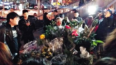 昨晚7時許，三里屯太古里西邊附近一過街天橋旁邊，聞訊而至的網(wǎng)友圍住了賣花老人，爭相買花。 網(wǎng)友“行者橙子”供圖