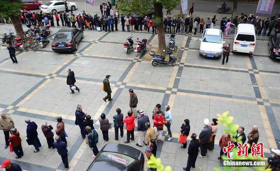 圖為10月28日，在江西九江市一家羊絨皮草服裝服飾博覽會現(xiàn)場，老人們正在頂著寒風排隊等待領(lǐng)取10元代金劵。