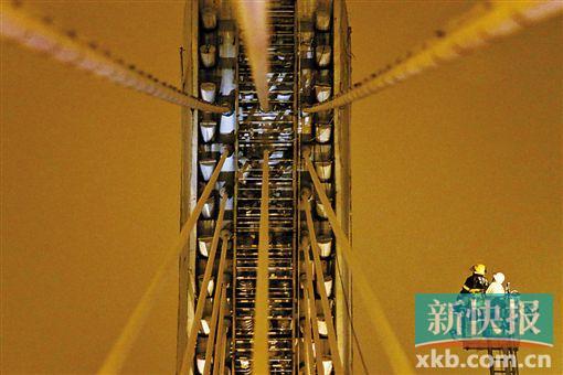 截至今日零時，男子仍未有下橋舉動。圖為公安和消防人員乘消防云梯在高空上和男子交談。